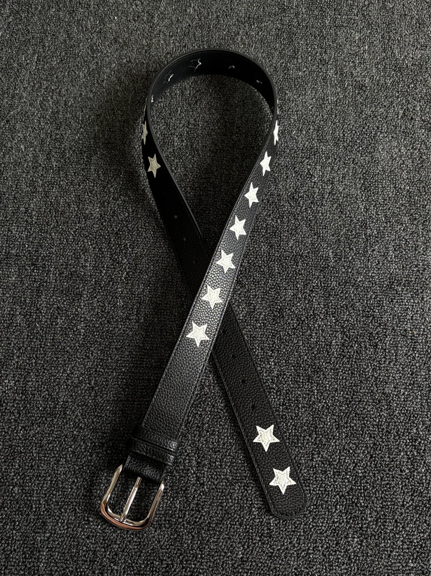 Black pebbled belt with white star inlays and a silver pin buckle