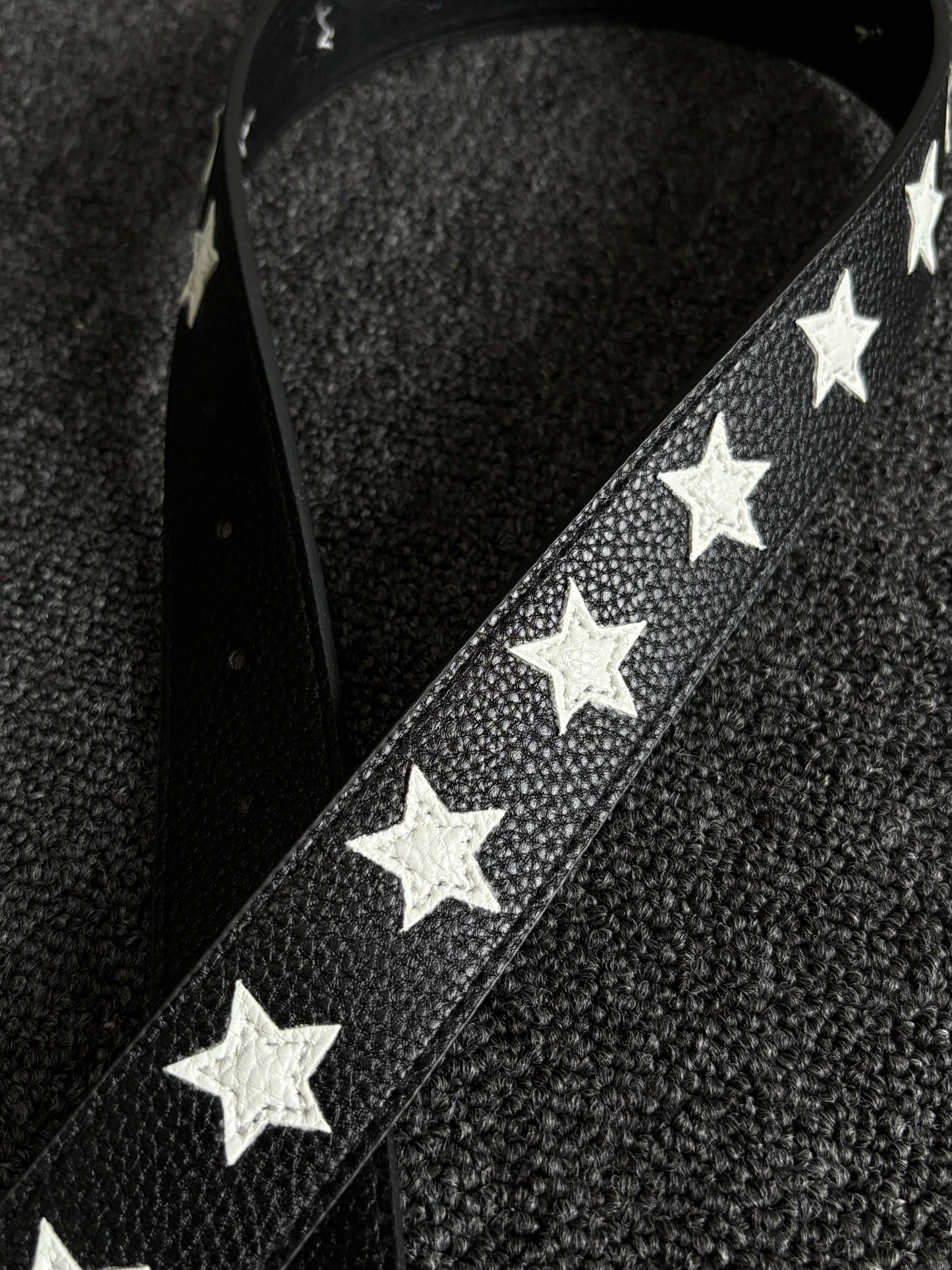 Black pebbled belt with white star inlays and a silver pin buckle