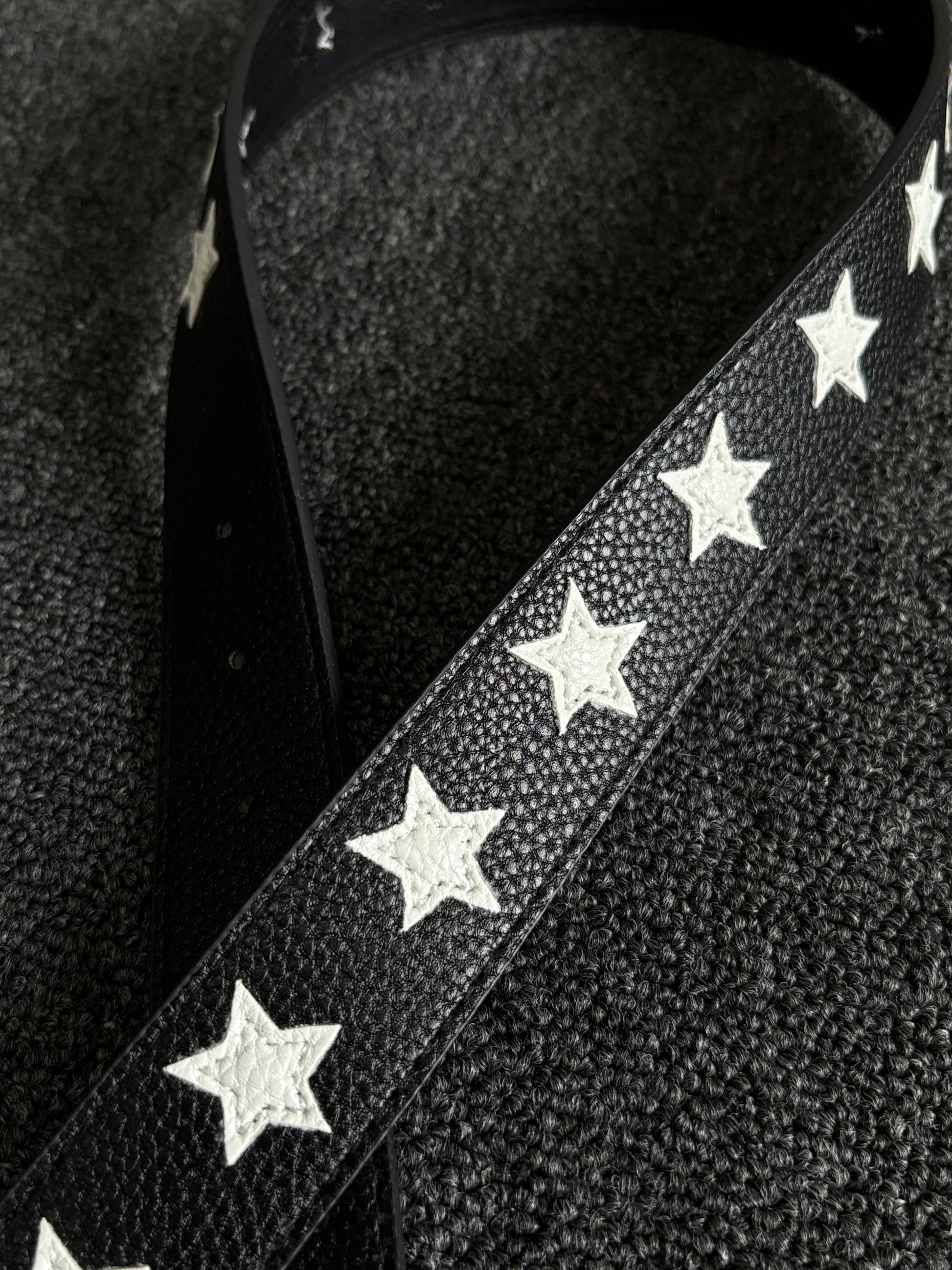 Black pebbled belt with white star inlays and a silver pin buckle