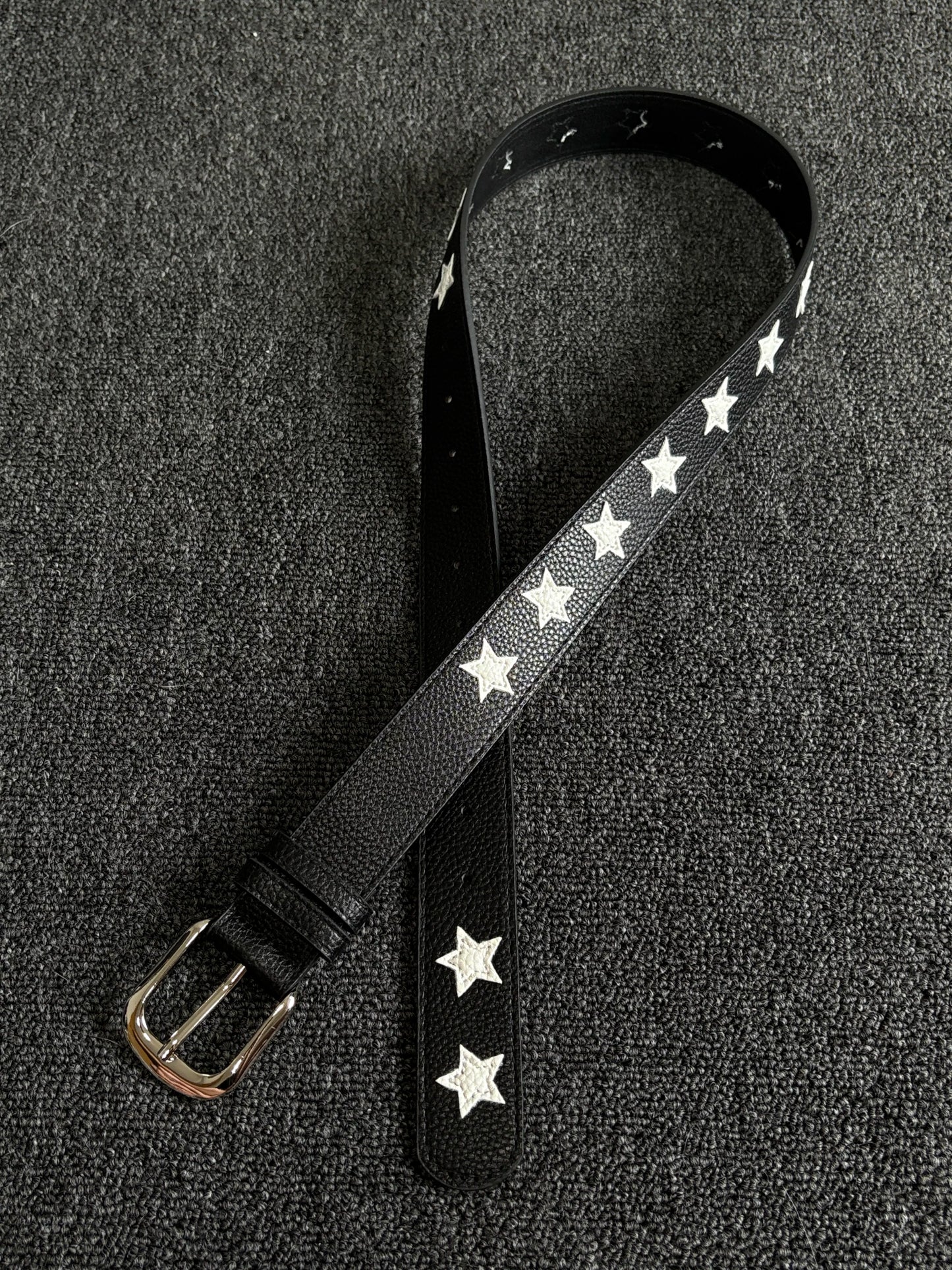 Black pebbled belt with white star inlays and a silver pin buckle
