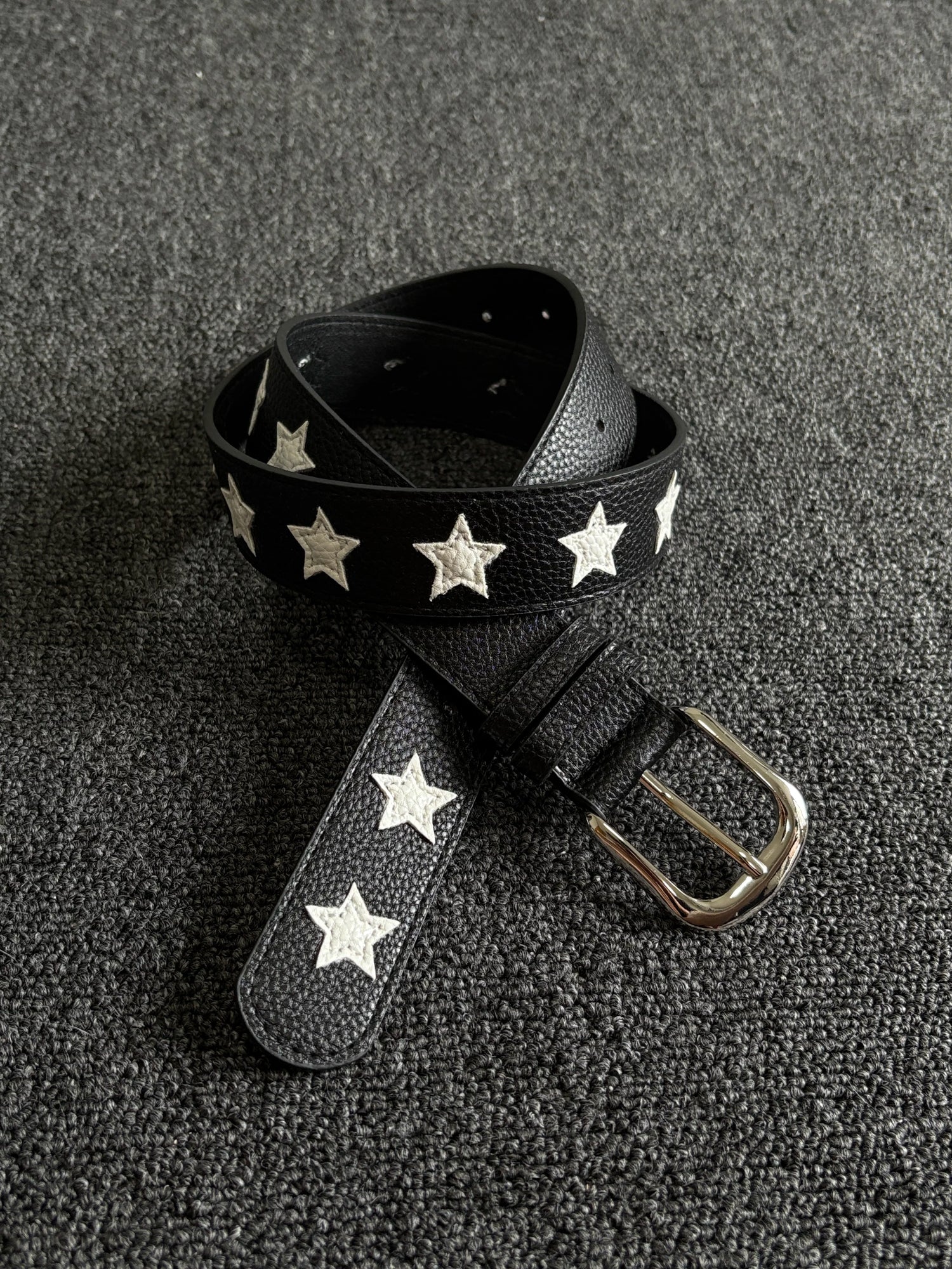 Black pebbled belt with white star inlays and a silver pin buckle