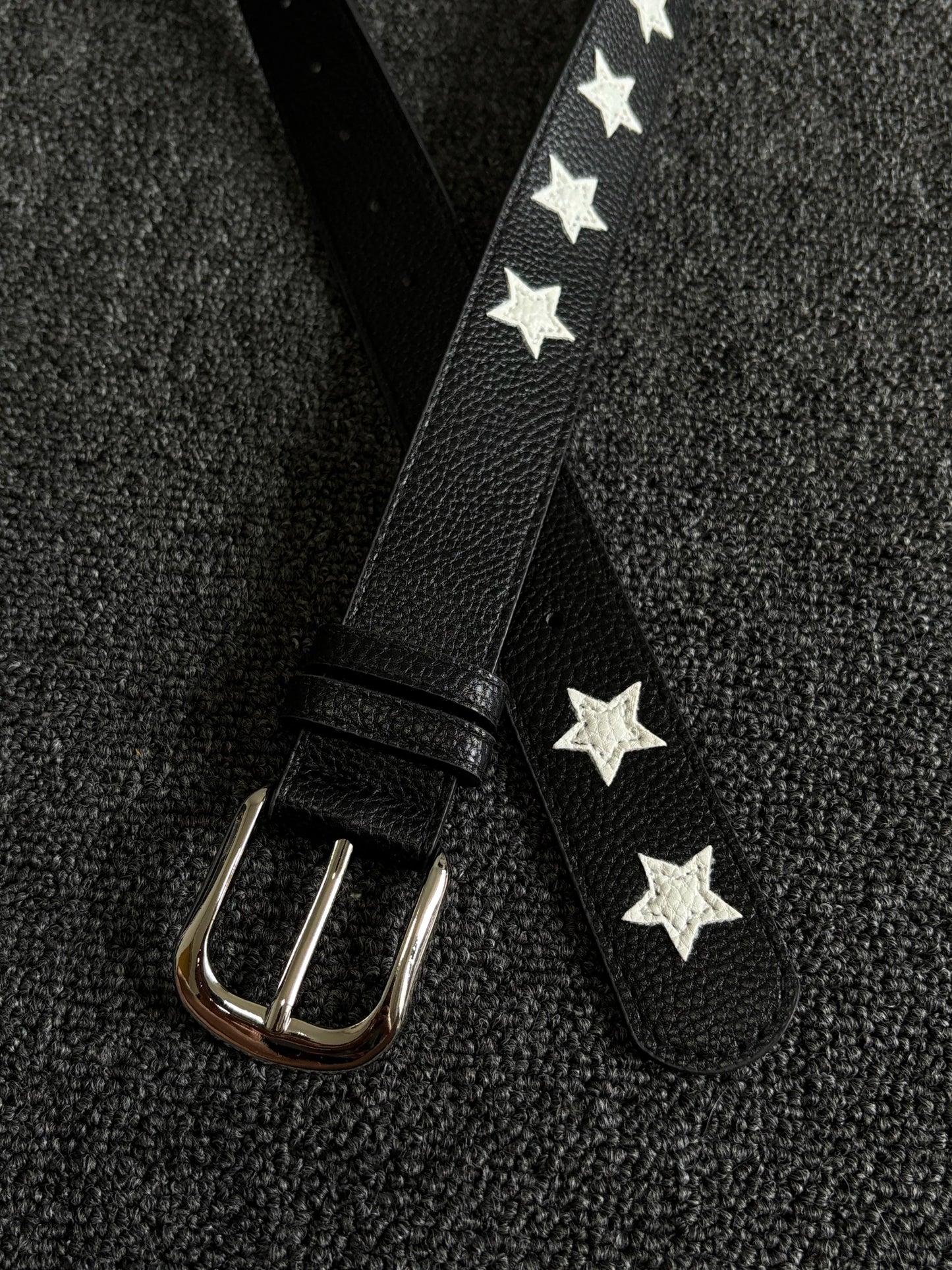 Black pebbled belt with white star inlays and a silver pin buckle