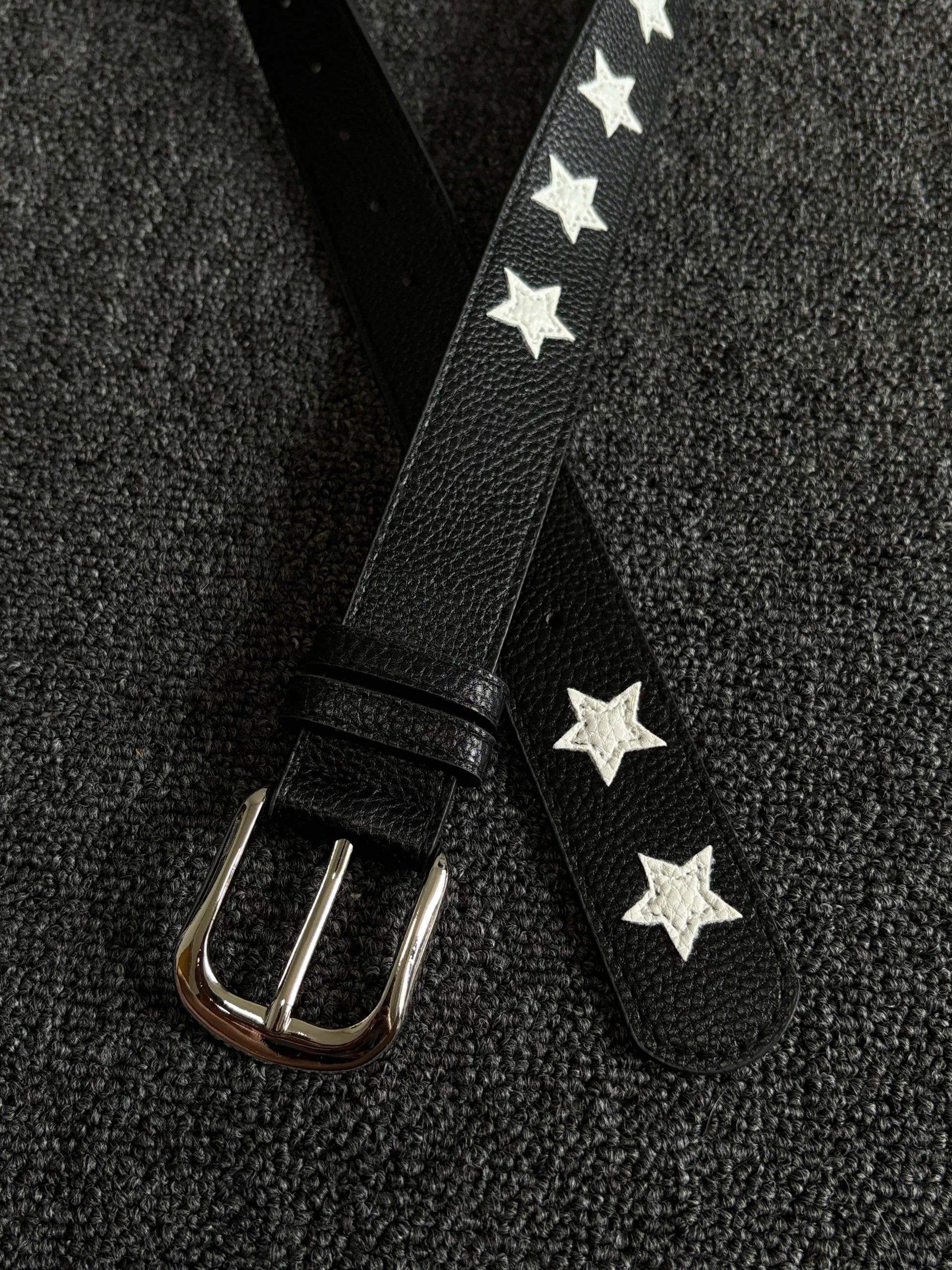 Black pebbled belt with white star inlays and a silver pin buckle