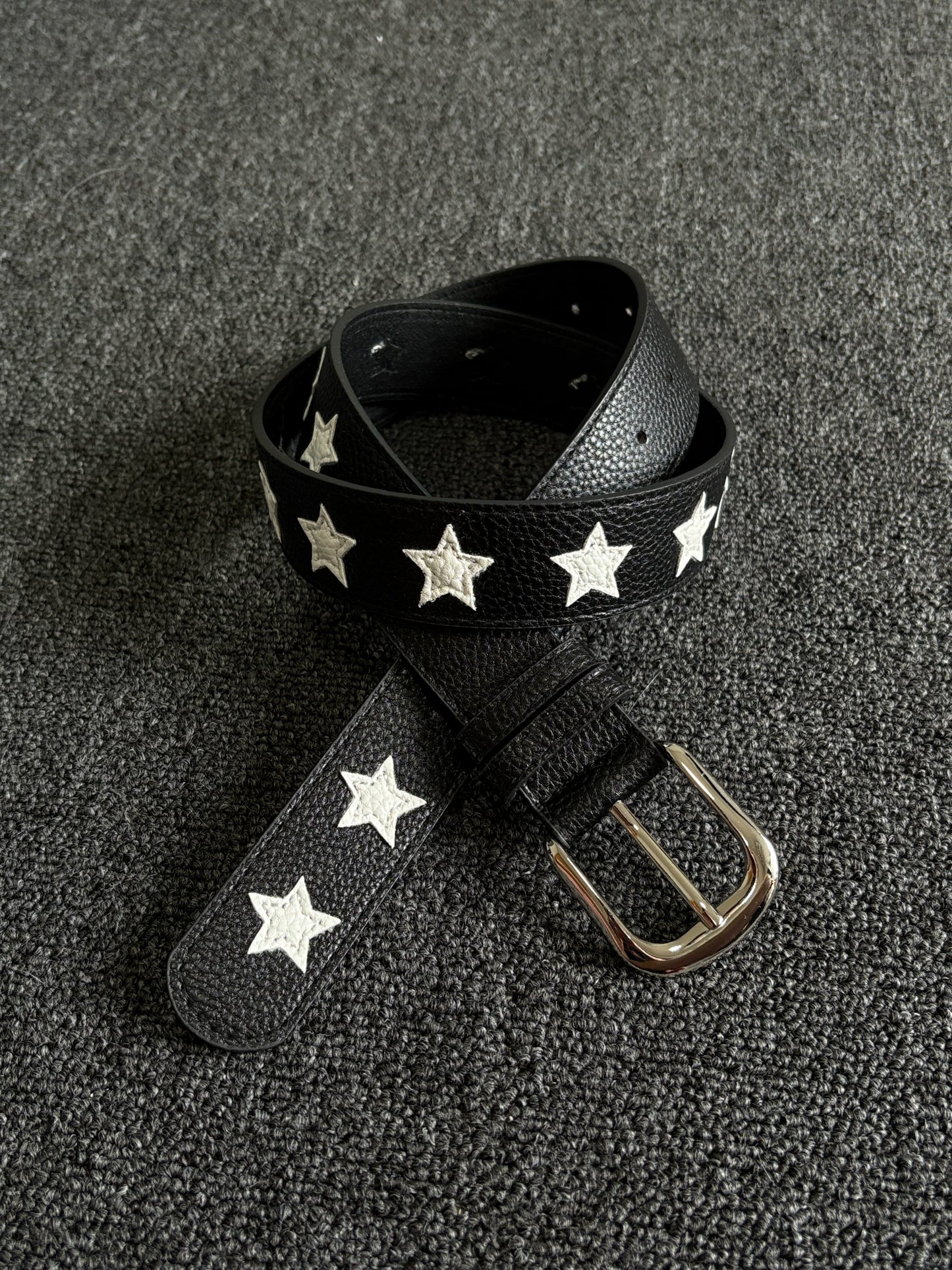 Black pebbled belt with white star inlays and a silver pin buckle