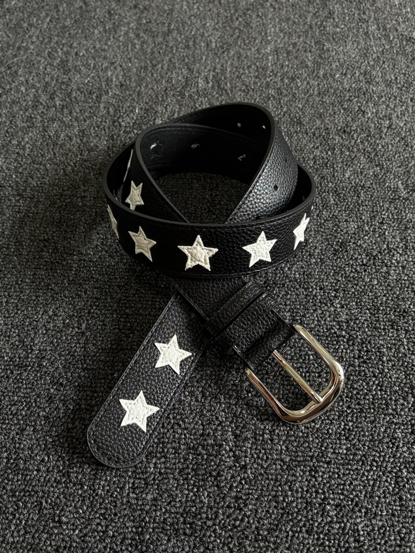Black pebbled belt with white star inlays and a silver pin buckle
